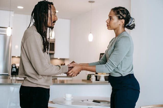 foto de uma mulher preta em pé de frente para um homem preto. Ela segura as mãos dele, demonstrando seu apoio e empatia.A imagem ilustra o artigo Empatia: A chave para a cura e compreensão escrito pelo psicanalista Homero Mônaco para o site Online Psicanalista.