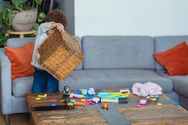 Foto de um menino pegando brinquedo em uma caixa de vime e colocando no chão para brincar. A foto ilustra o artigo "Terapia da Brincadeira" escrito pelo psicanalista Homero Monaco para o site online psicanalista.