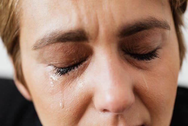 Foto do rosto de uma mulher chorando pelo luto. A foto ilustra o artigo 10 Estágios do Luto: Lidando com a Perda escrito pelo psicanalista Homero Mônaco para o site Online Psicanalista.