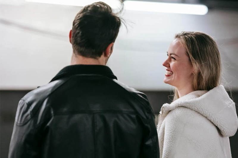 Foto de um casal de namorados sentados, uma está olhando para o outro e a mulher está confiante e sorridente. A foto ilustra o artigo 5 Melhores Maneiras de Aumentar a sua Confiança nos Relacionamentos escrito pelo psicanalista Homero Monaco para o site Online Psicanalista.