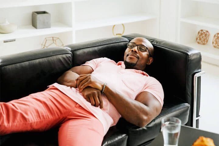 Foto de um homem negro, deitado em um sofá, como se estivesse em uma sessão de terapia. A foto ilustra o artigo 10 Passos para Alcançar Equilíbrio Emocional Através da Psicanálise escrito pelo psicanalista Homero Mônaco para o site Online Psicanalista.