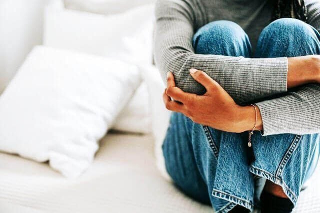 Foto de uma mulher sentada no chão toda encolhida como se estivesse com uma crise de depressão. A foto ilustra o artigo 25 Sinais e Sintomas da Depressão que você deve ficar atento escrito pelo psicanalista Homero Mônaco para o site Online Psicanalista.