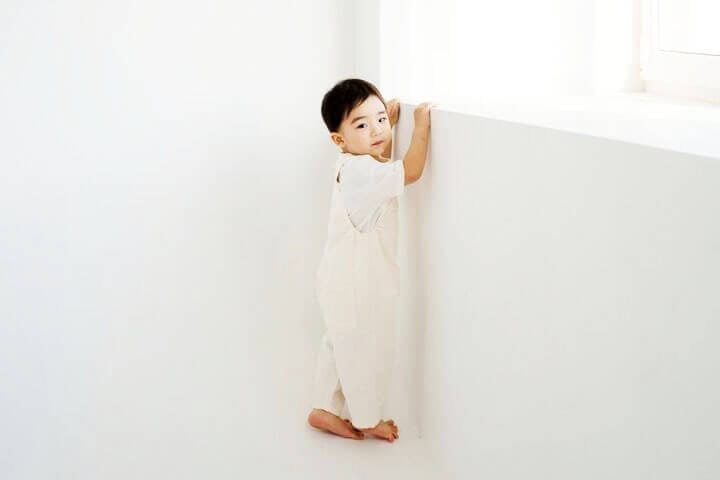 Foto de um menino oriental nas pontas dos pés, como se quisesse crescer, para poder ver através da janela. O menino usa camiseta branca, macacão branco e está em um quarto branco. A foto ilustra o artigo Por que desconstruir os seus padrões comportamentais por meio da sua aceitação e da sua transformação escrito pelo psicanalista Homero Mônaco para o site Online Psicanalista.Foto de uma menina com perna levantada como se fosse pisar na lente da câmera que a fotografa. A foto ilustra o artigo Alcançar a Paz e o Encerramento de Decepções Passadas escrito pelo psicanalista Homero Mônaco para o site Online Psicanalista.