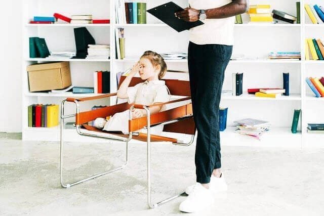 Foto de uma menina de aproximadamente 8 anos sentada na cadeira de consultório de um psicanalista enquanto ele está de pé ao seu lado anotando algo no tablet. A foto ilustra o artigo O tratamento psicanalítico pode apagar completamente as cicatrizes emocionais? escrito pelo psicanalista Homero Mônaco para o site Online Psicanalista. Foto de uma menina com perna levantada como se fosse pisar na lente da câmera que a fotografa. A foto ilustra o artigo Por que a psicanálise oferece ajuda genuína para fobias? escrito pelo psicanalista Homero Mônaco para o site Online Psicanalista.