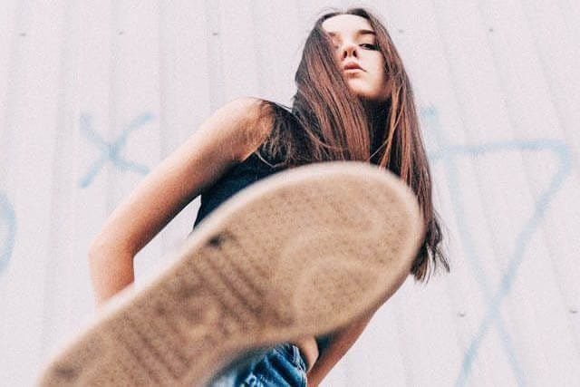Foto de uma menina com perna levantada como se fosse pisar na lente da câmera que a fotografa. A foto ilustra o artigo Por que desconstruir os seus padrões comportamentais por meio da sua aceitação e da sua transformação escrito pelo psicanalista Homero Mônaco para o site Online Psicanalista.