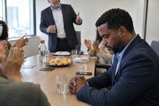 Pessoa recebe elogios por suas conquistas profissionais, mas demonstra dificuldade em acolher o reconhecimento. A cena representa a distância entre os resultados alcançados e a percepção que alguém tem do próprio valor. Imagem utilizada para ilustrar o artigo “Sentir-se uma fraude mesmo com tantas conquistas tem explicação real” escrito por Homero Mônaco Psicanalista especializado em neurociências e comportamento.